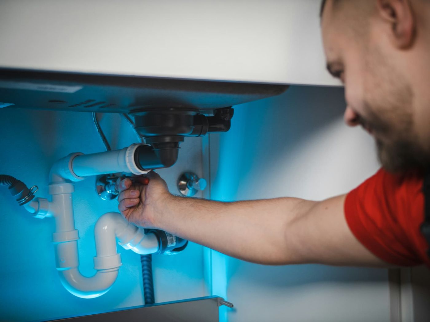 Apex engineer fixing pipework under a sink